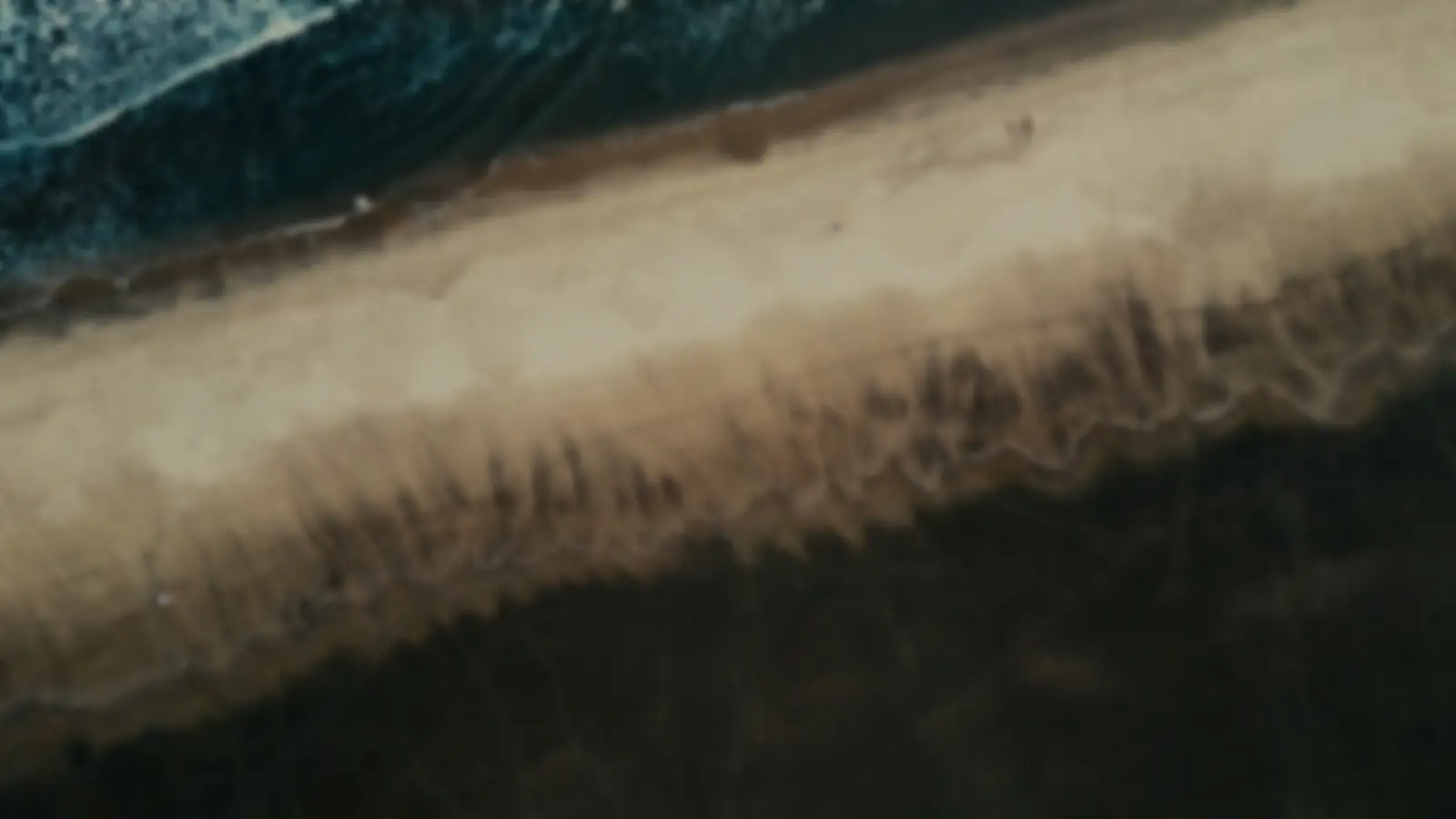 Abstrakte Nahaufnahme eines Sandstrands im Header-Bereich – Beruhigendes Hintergrundbild in kühlen Blau- und Beigetönen mit subtilem Lichteffekt.